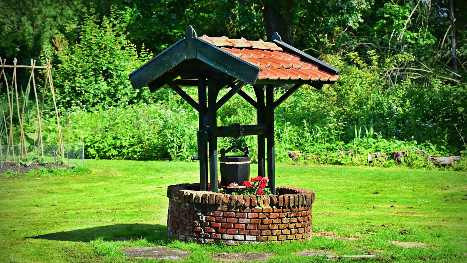 Puits traditionnel en pierre dans un jardin potager